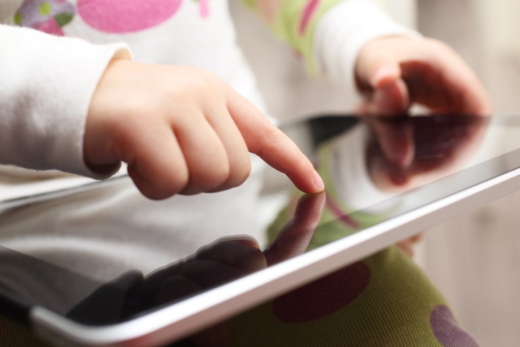 Close-up of a child playing on a touch screen tablet