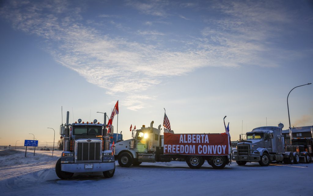 A truck convoy of anti-COVID-19 vaccine mandate demonstrators block the highway at the busy U.S. border crossing in Coutts, Alta., Wednesday, Feb. 2, 2022. THE CANADIAN PRESS/Jeff McIntosh