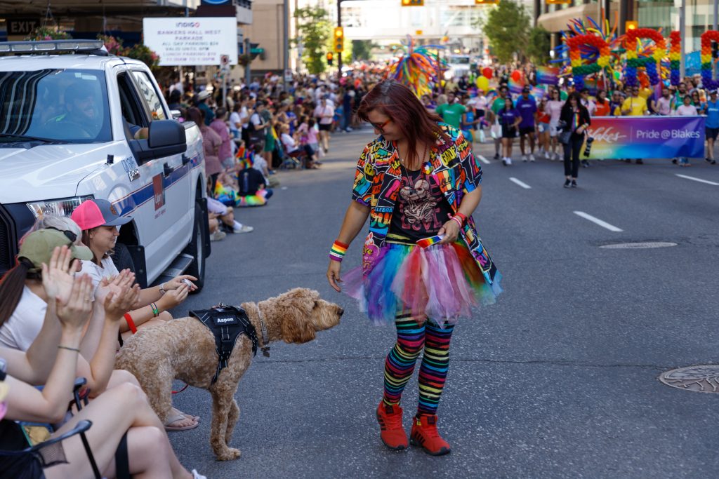 A dog approaches a Pride Parade participant in downtown Calgary