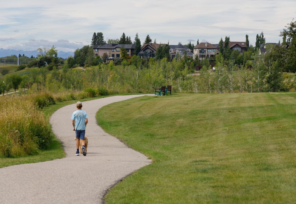 A boy walks his dog along a path in the Discovery Ridge neighbourhood in Calgary on Friday, Aug. 30, 2024