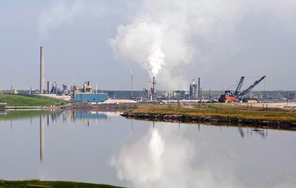 In the absence of public communication from the Pathways Alliance, a clean energy think-tank says the oilsands industry group is running out of time to deliver on its emissions reduction promises. An oilsands facility is reflected in a tailings pond near Fort McMurray, Alta., on July 10, 2012. THE CANADIAN PRESS/Jeff McIntosh