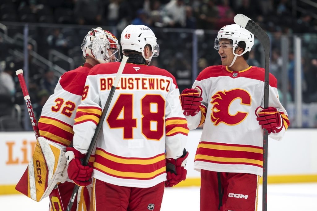 Calgary Flames defensemen Zayne Parekh, right, and Hunter Brzustewicz (48) celebrate with goaltender Dustin Wolf (32) after defeating the Seattle Kraken in a preseason NHL hockey game Sunday, Sept. 22, 2024, in Seattle. (AP Photo/Jason Redmond)