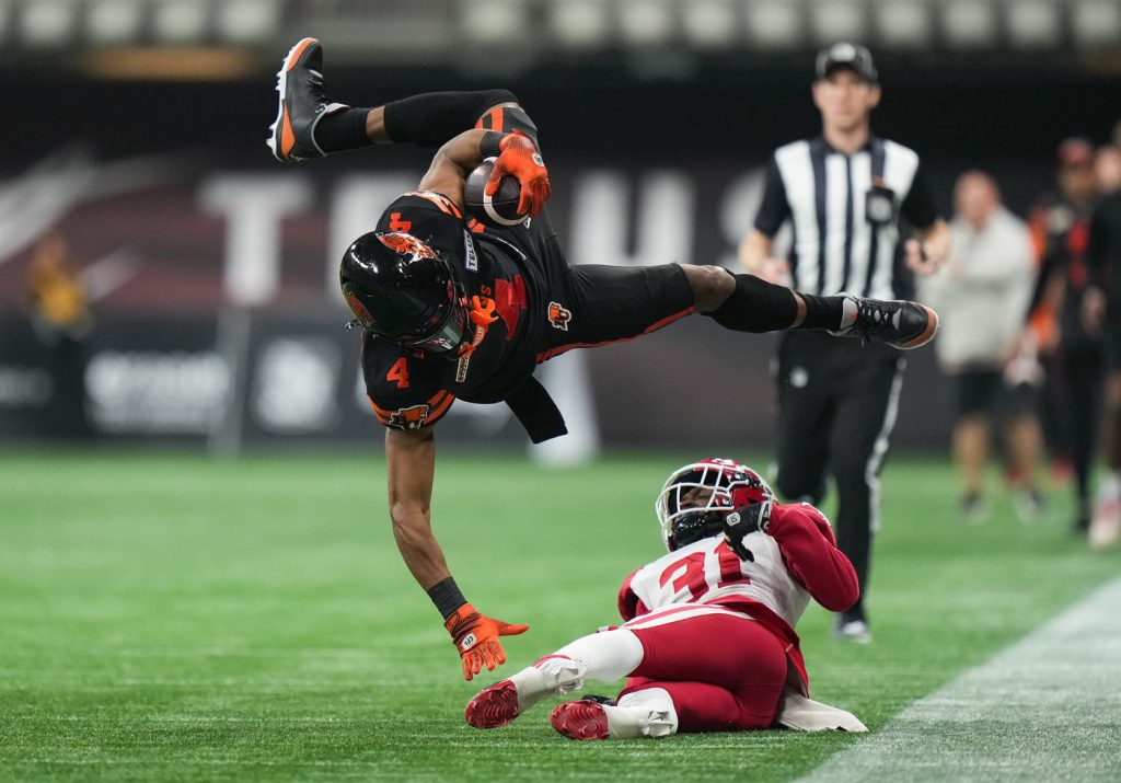 B.C. Lions' Keon Hatcher Sr. (4) is upended by Calgary Stampeders' Tre Roberson (31) after making a reception and running with the ball for a 50-yard gain during the second half of a CFL football game, in Vancouver