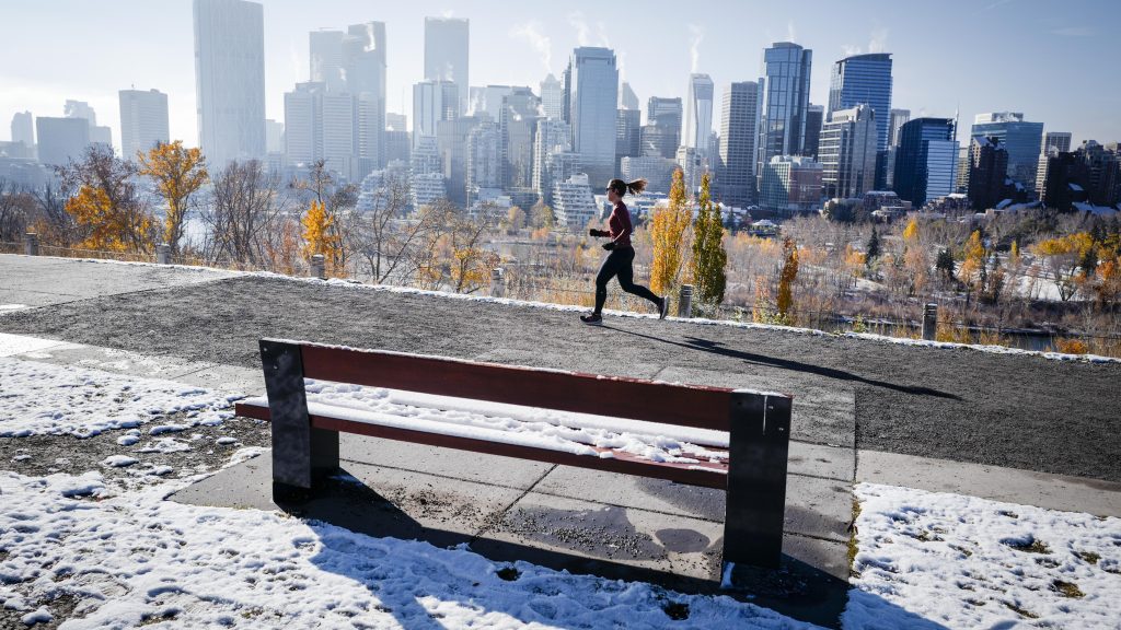 A person runs along a pathway near downtown Calgary after a snowfall on Oct. 22, 2024. THE CANADIAN PRESS/Jeff McIntosh