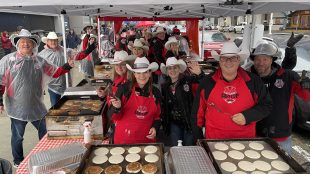 Members of the Calgary Grey Cup Committee pose for a photo while they serve pancakes