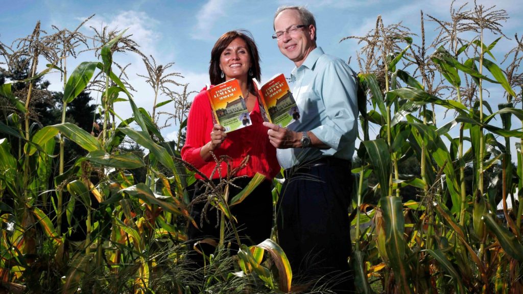 FILE - Farmers' Almanac editor Sondra Duncan and publisher Peter Geiger pose in a corn field with the 2012 edition of the almanac, Aug. 24, 2011, in Auburn, Maine. (AP Photo/Robert F. Bukaty, File)