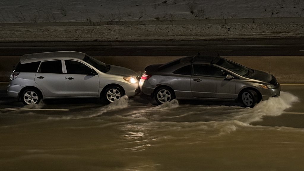 Two vehicles shown after they were caught by water that burst from a main in northwest Calgary in the area of the Sarcee Trail and 16 Avenue NW interchange on Tuesday, Dec. 30, 2025