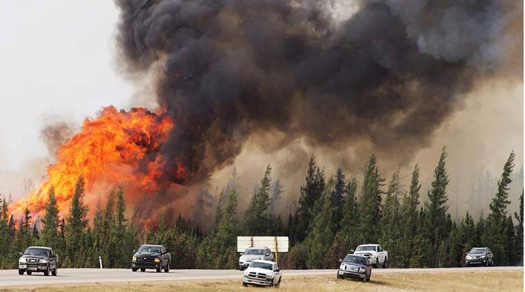 A convoy of evacuees from Fort McMurray, Alberta drive past wildfires that are still burning out of control as they leave the city
